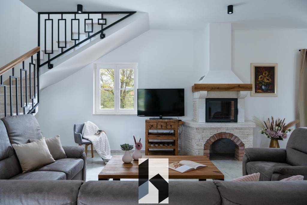 Gemütliches Wohnzimmer mit Kamin, bequemen Sofas und Treppe zum Obergeschoss.