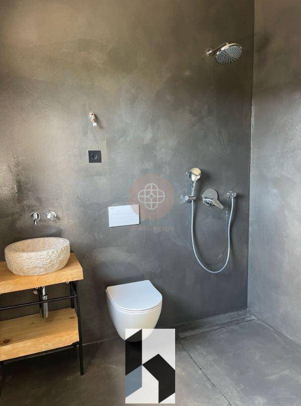 Modernes Badezimmer mit begehbarer Dusche, Steinwaschbecken und Wand-WC in dunklem Design.