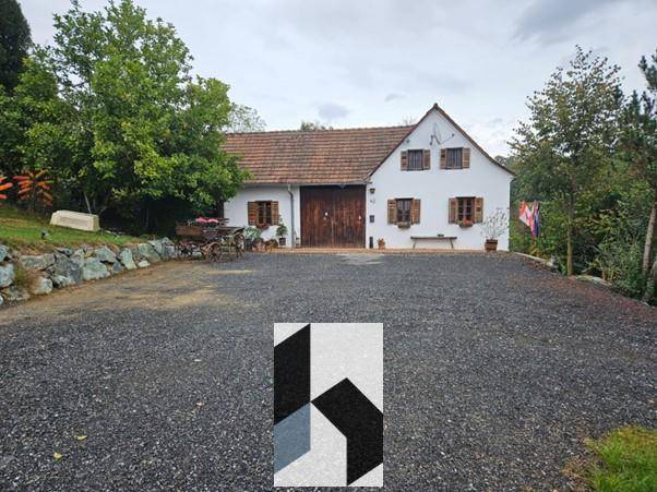 Weißes Landhaus mit großem Kiesweg und umgebender grüner Landschaft.