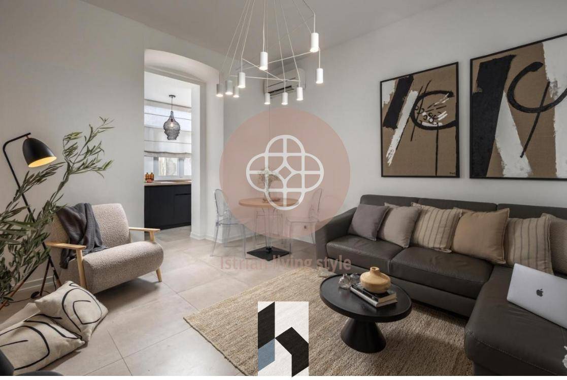 Modernes Wohnzimmer mit beigem Sofa, Couchtisch und Blick in die offene Küche.