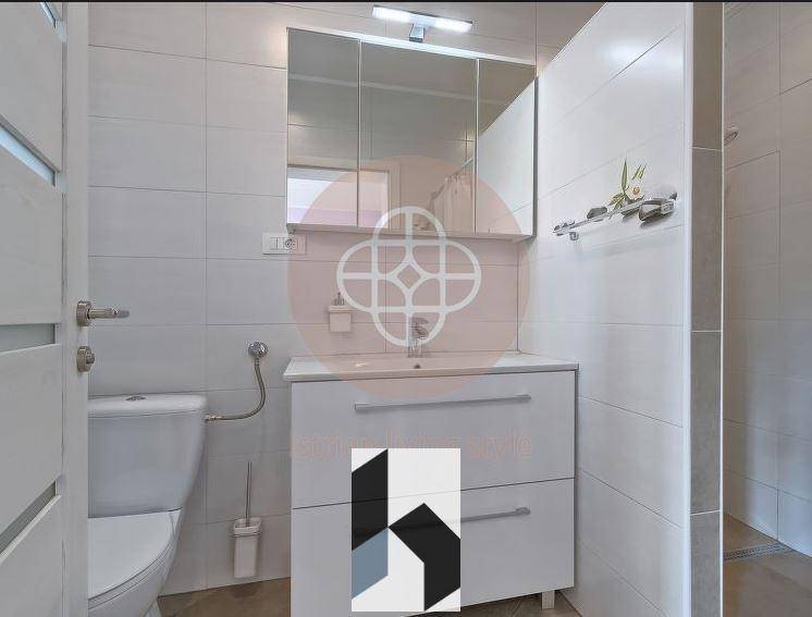 Helles Badezimmer mit Waschtisch, Spiegelschrank und Duschbereich.