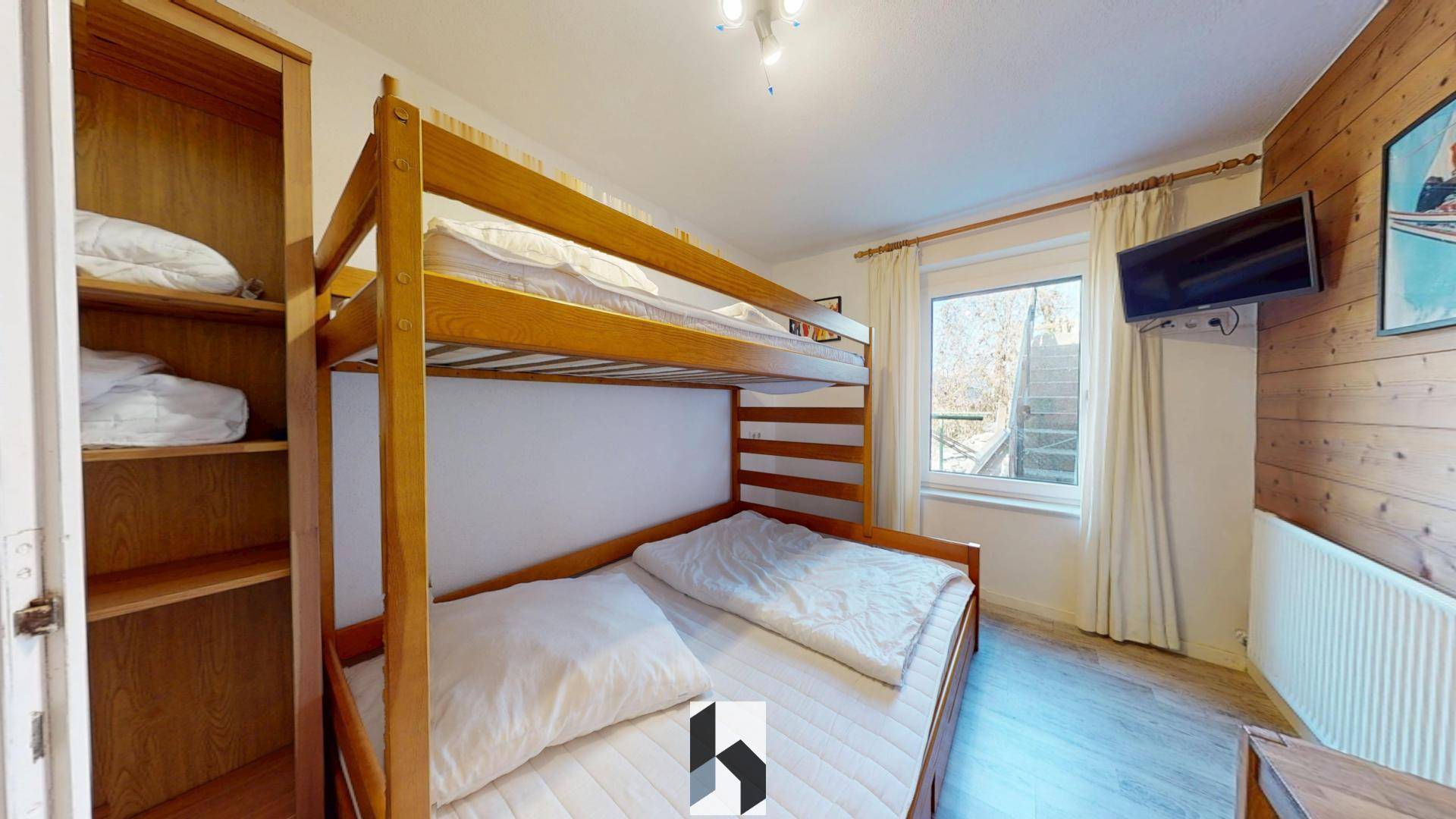 Kinderfreundliches Schlafzimmer mit Etagenbett, Holzvertäfelung und Blick ins Grüne durch das Fenster.