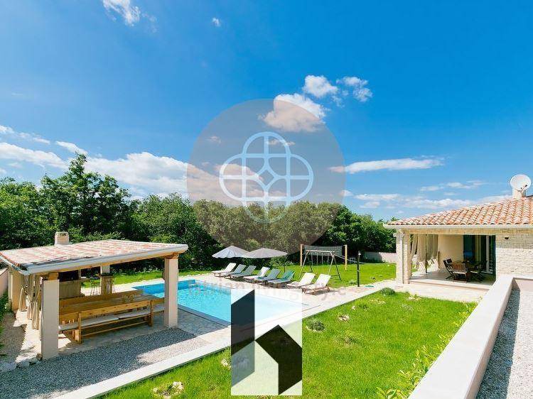 Großer Poolbereich mit Sonnenliegen und angrenzendem Garten unter blauem Himmel.