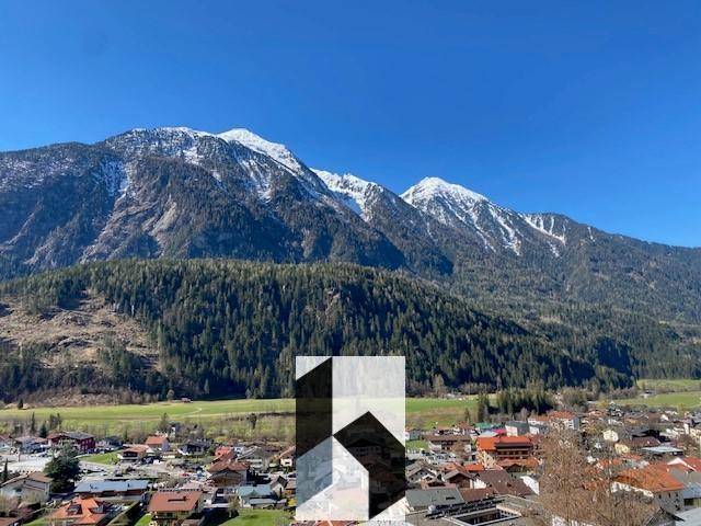 Atemberaubender Blick auf schneebedeckte Berge über einer grünen Talandschaft unter strahlend blauem Himmel.