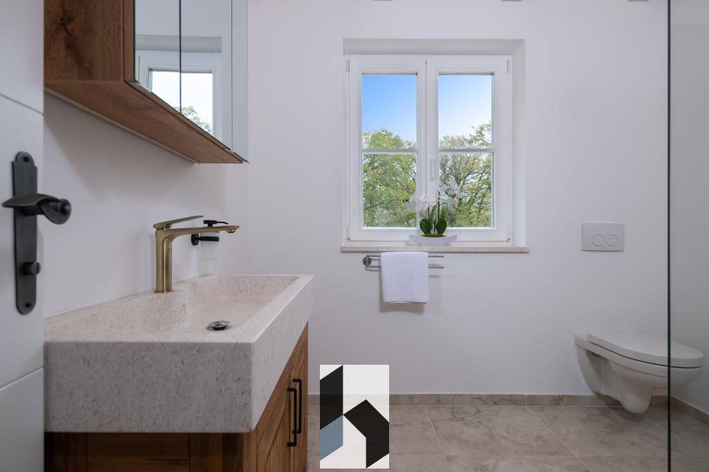 Modernes Badezimmer mit Waschtisch, wandhängendem WC und Fenster für Tageslicht.