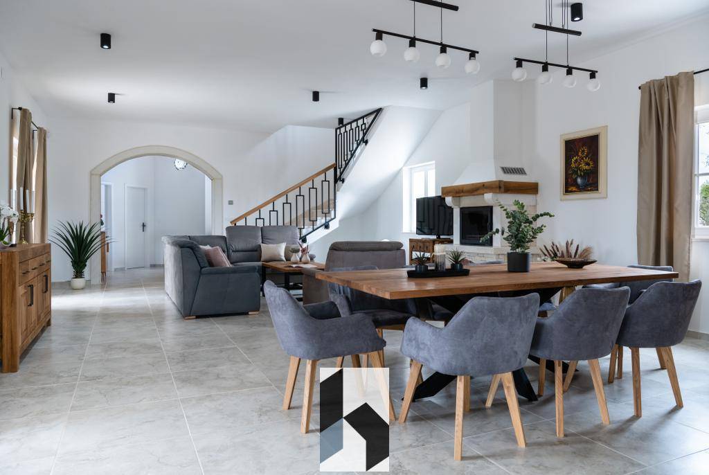 Offener Wohn- und Essbereich mit Fliesenboden, Kamin und eleganter Treppe.