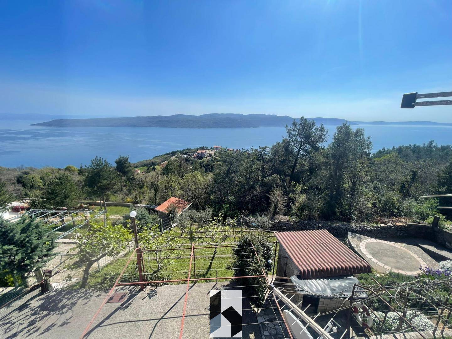 Weitläufiger Außenbereich mit Meerblick, umgeben von viel Grün und mediterraner Landschaft.