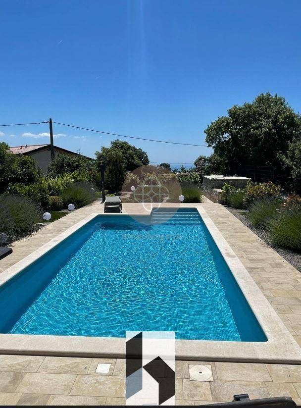 Rechteckiger Swimmingpool mit gefliester Umrandung und klarem blauen Wasser.