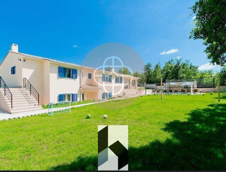 Überdachte Terrasse mit großem Esstisch und Blick auf den Poolbereich und Garten.