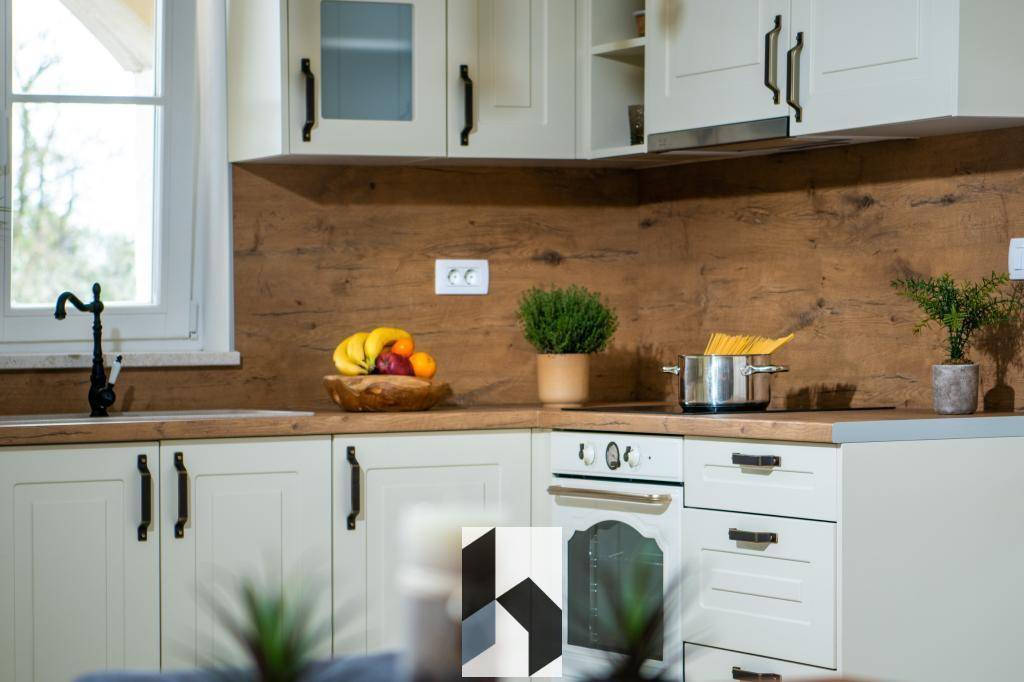 Helle Küche mit cremefarbenen Schränken, Holzrückwand und modernen Geräten.