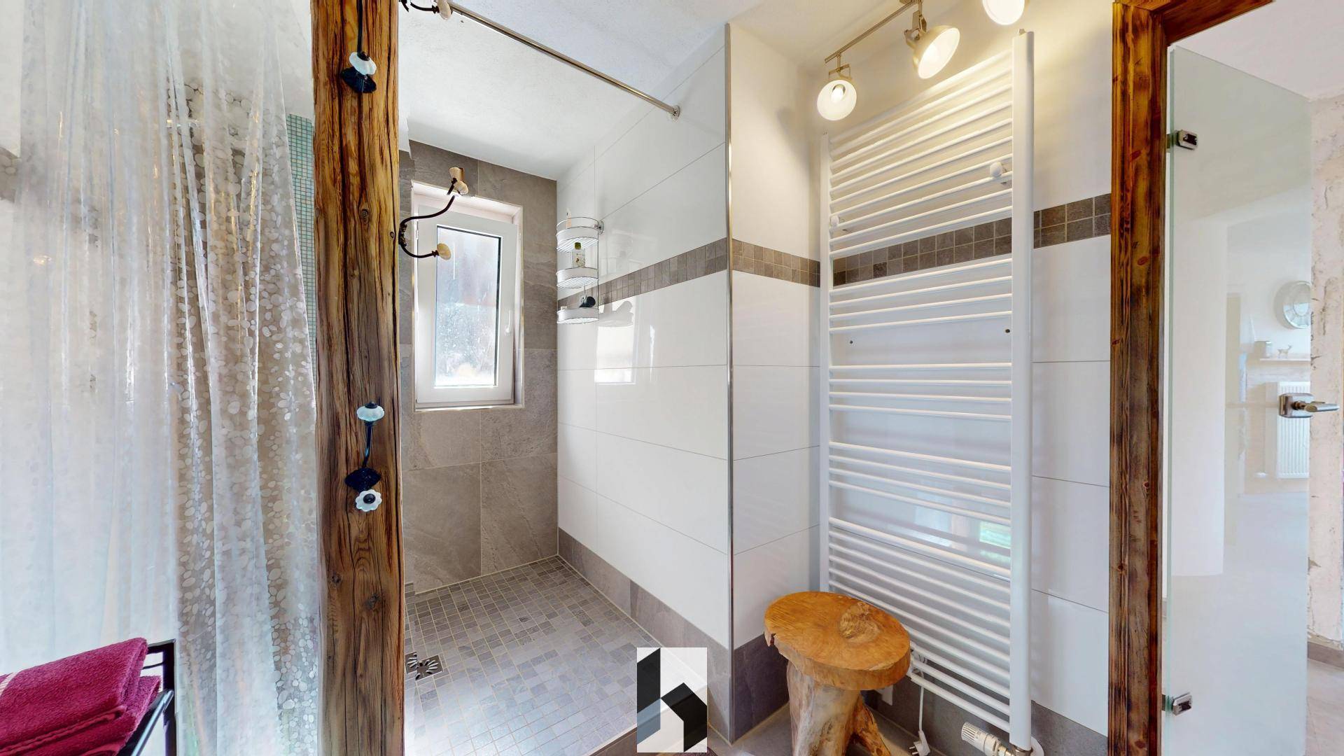 Modernes Duschbad mit Fliesen, Holzdetails und beheiztem Handtuchhalter, hell und funktional.
