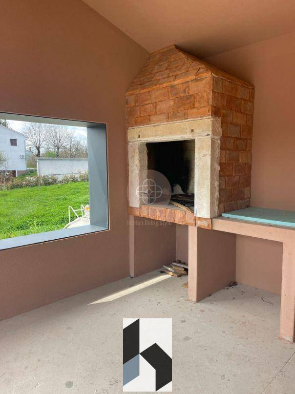 Überdachter Außenbereich mit gemauertem Grillkamin und Arbeitsfläche, ideal für gesellige Abende.
