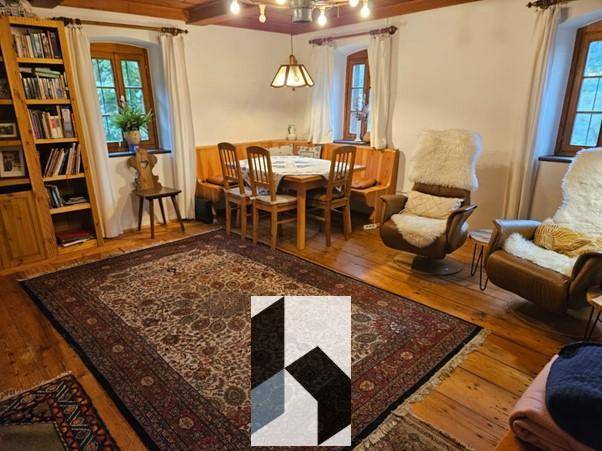 Geräumiger Wohn-Essbereich mit Holzboden, großem Teppich und gemütlichen Sitzgelegenheiten.