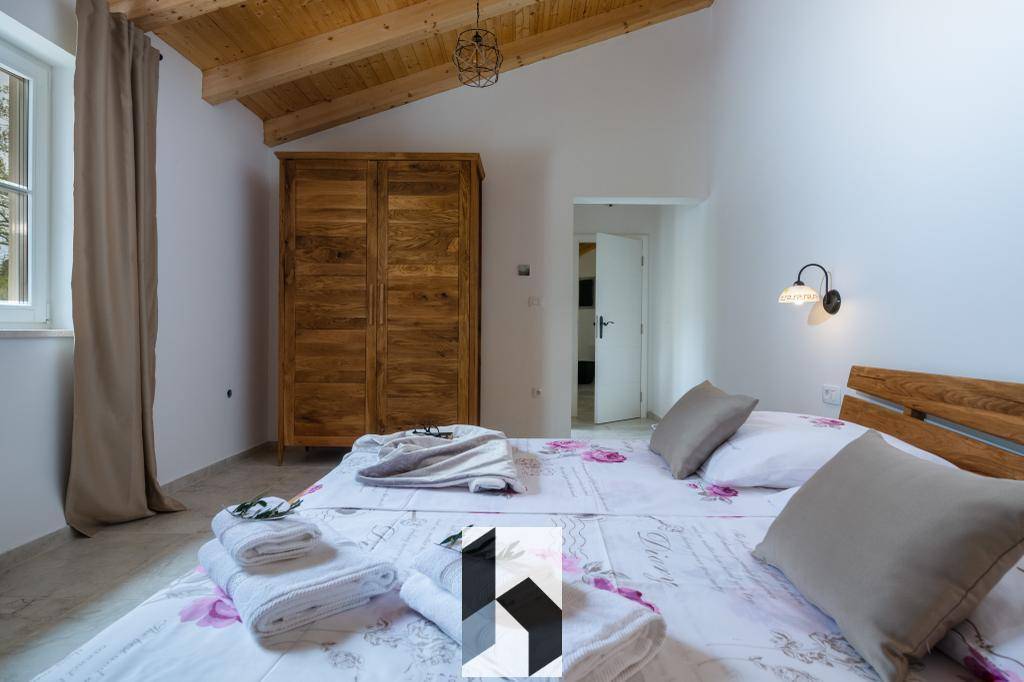 Schlafzimmer mit zwei Einzelbetten, Holzschrank und sichtbarer Holzdachkonstruktion.
