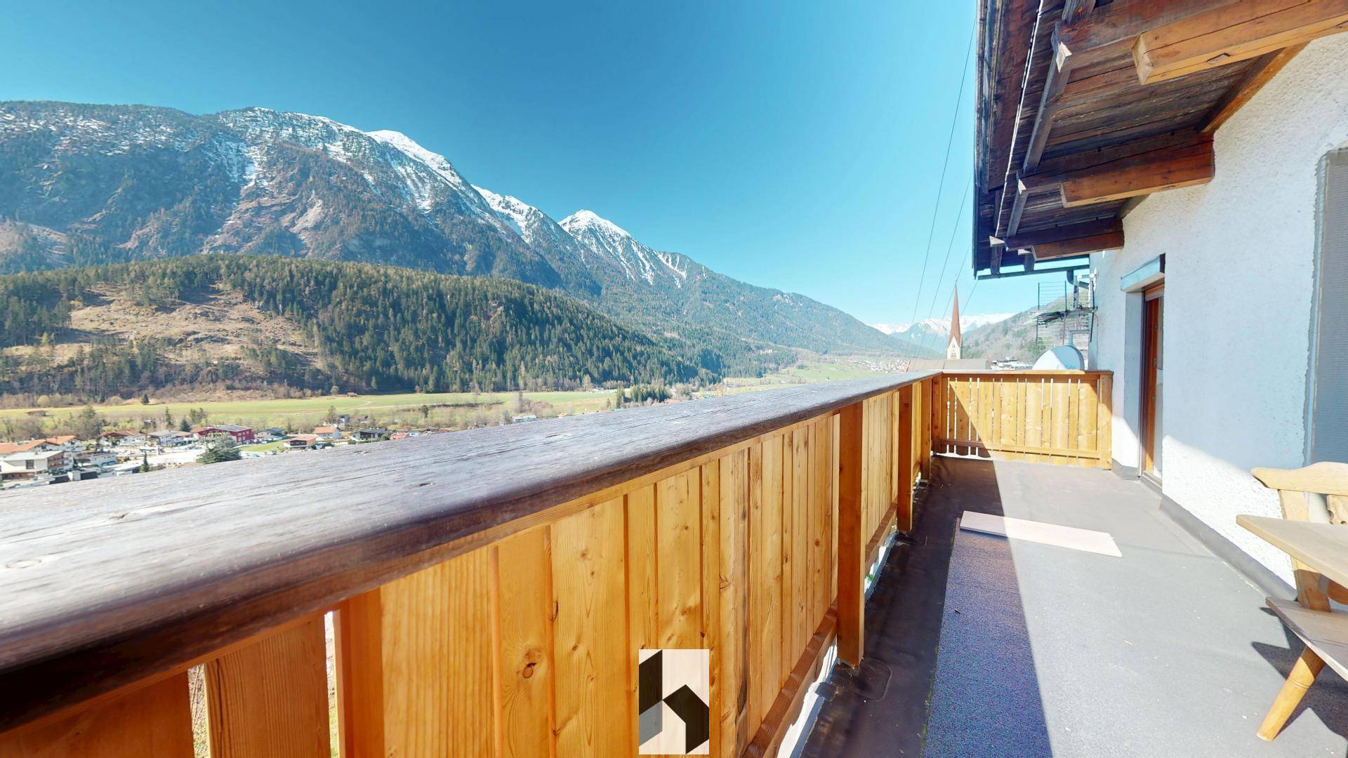 Geräumiger Holzbalkon mit Panoramablick auf die Berge und das Tal, perfekt zum Entspannen.