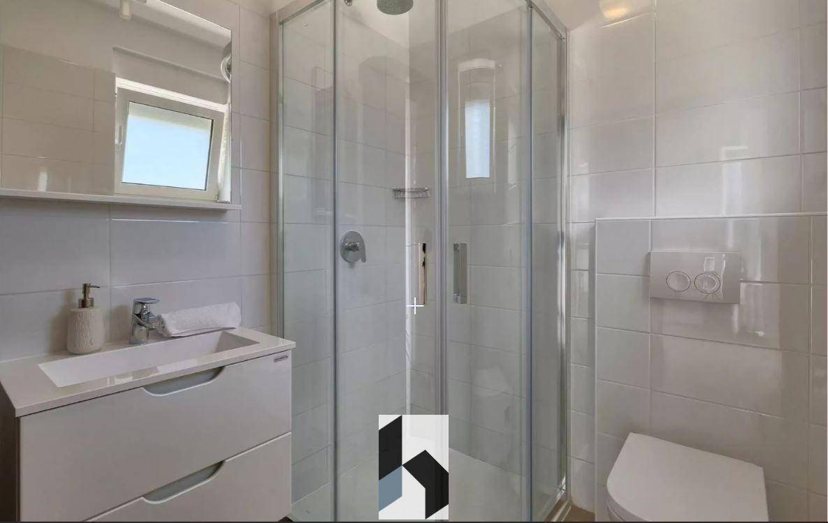Modernes Badezimmer mit Duschkabine, Einzelwaschbecken und Fenster für Tageslicht.
