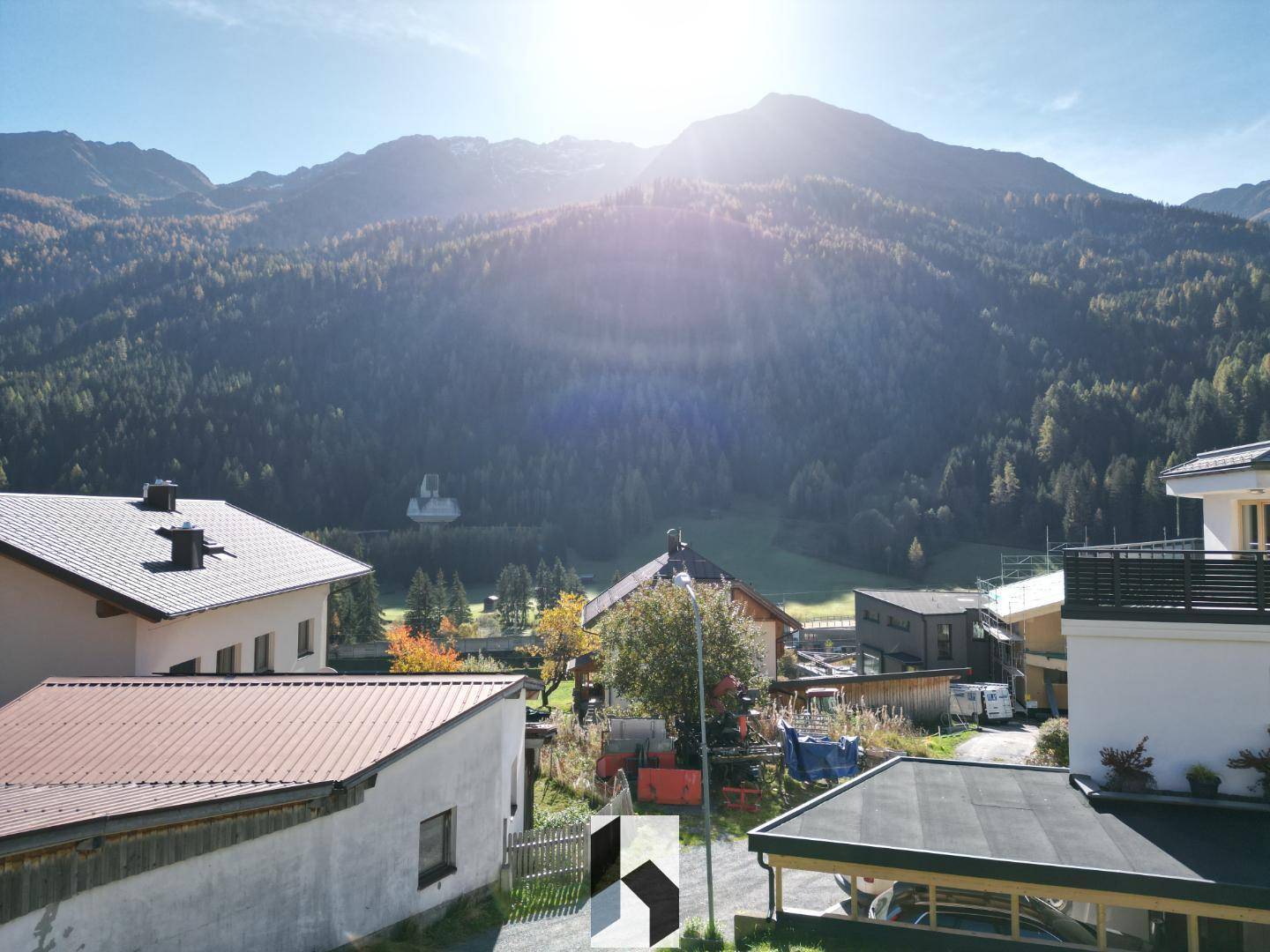 Panoramablick auf die umliegende Berglandschaft mit bewaldeten Hängen und strahlendem Sonnenschein.