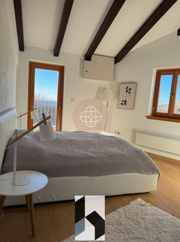 Helles Schlafzimmer mit Holzbalken, Holzboden und moderner Einrichtung.