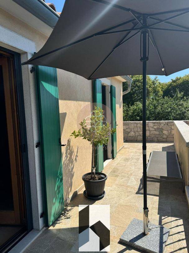 Sonniger Balkon mit Fliesenboden, Sonnenschirm und Blick ins Grüne.