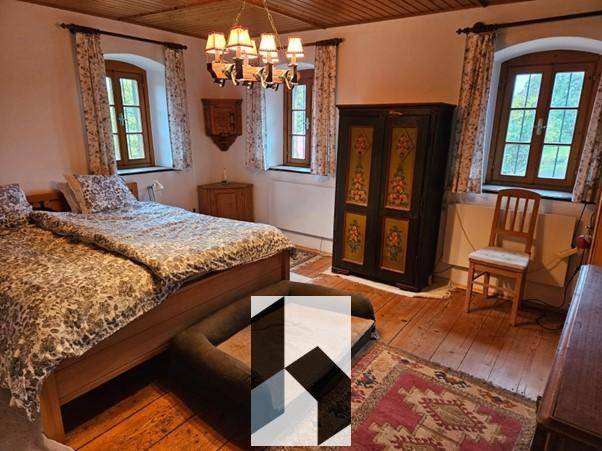 Schlafzimmer mit Holzboden, Doppelbett und einem kunstvoll bemalten Kleiderschrank.