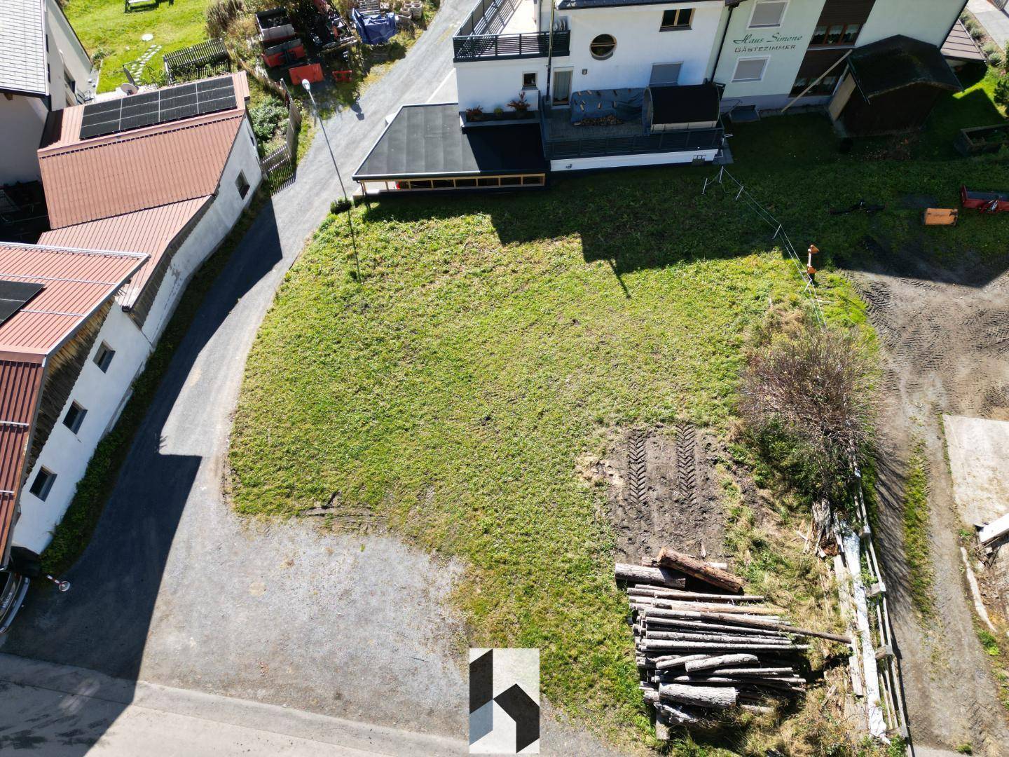 Drohnenansicht des Baugrundstücks mit angrenzenden Häusern und Solaranlagen auf den Dächern.