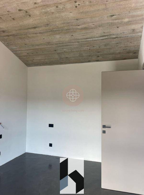 Leerer Raum mit weiß gestrichenen Wänden, Betonboden und freiliegender Betondecke, noch im Bau.
