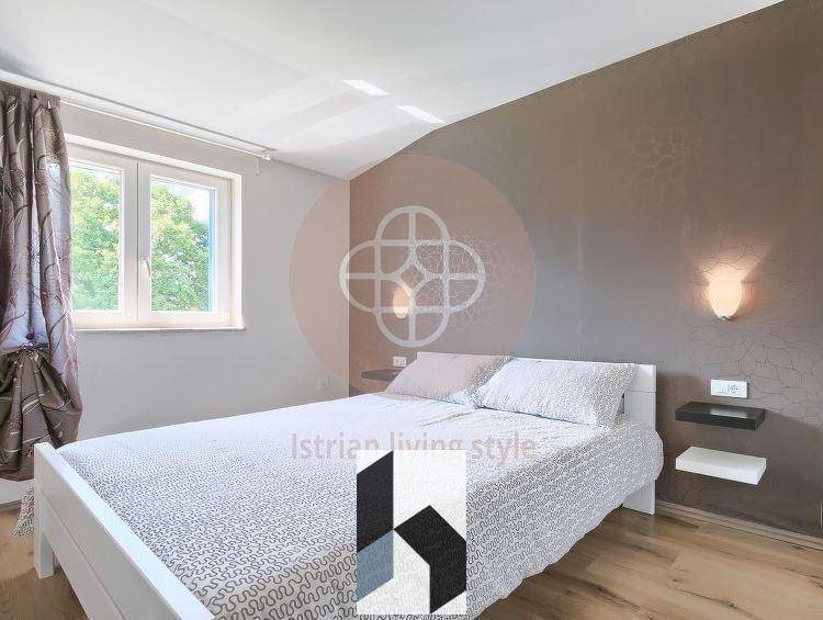 Schlafzimmer mit Doppelbett, Holzboden und Fenster mit Blick ins Grüne.