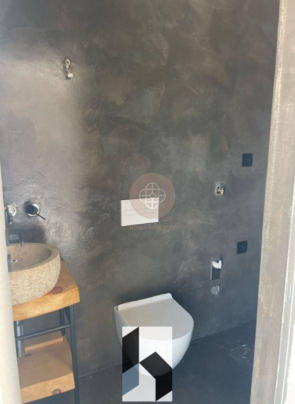 Detailansicht eines modernen Badezimmers mit Steinwaschbecken und Wand-WC in dunkler Ästhetik.