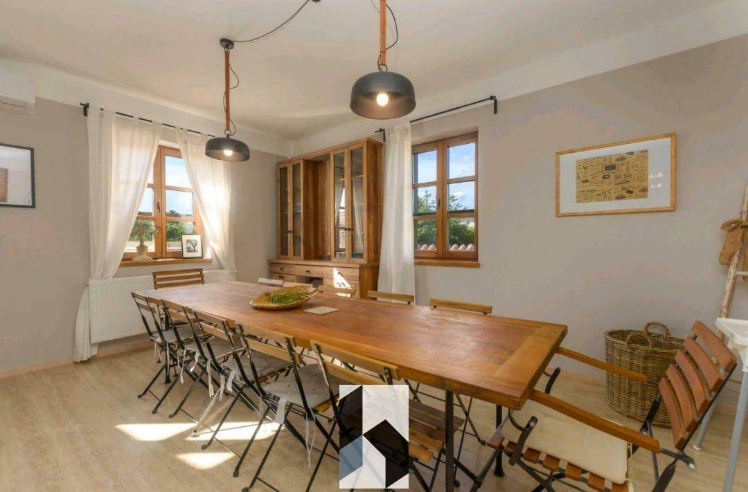 Geräumiger Essbereich mit großem Holztisch und vielen Sitzgelegenheiten, hell durch Fenster.