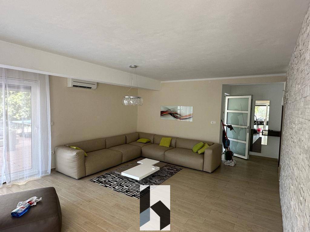 Helles Wohnzimmer mit großem Ecksofa, modernen Fliesen und Zugang zur Terrasse.