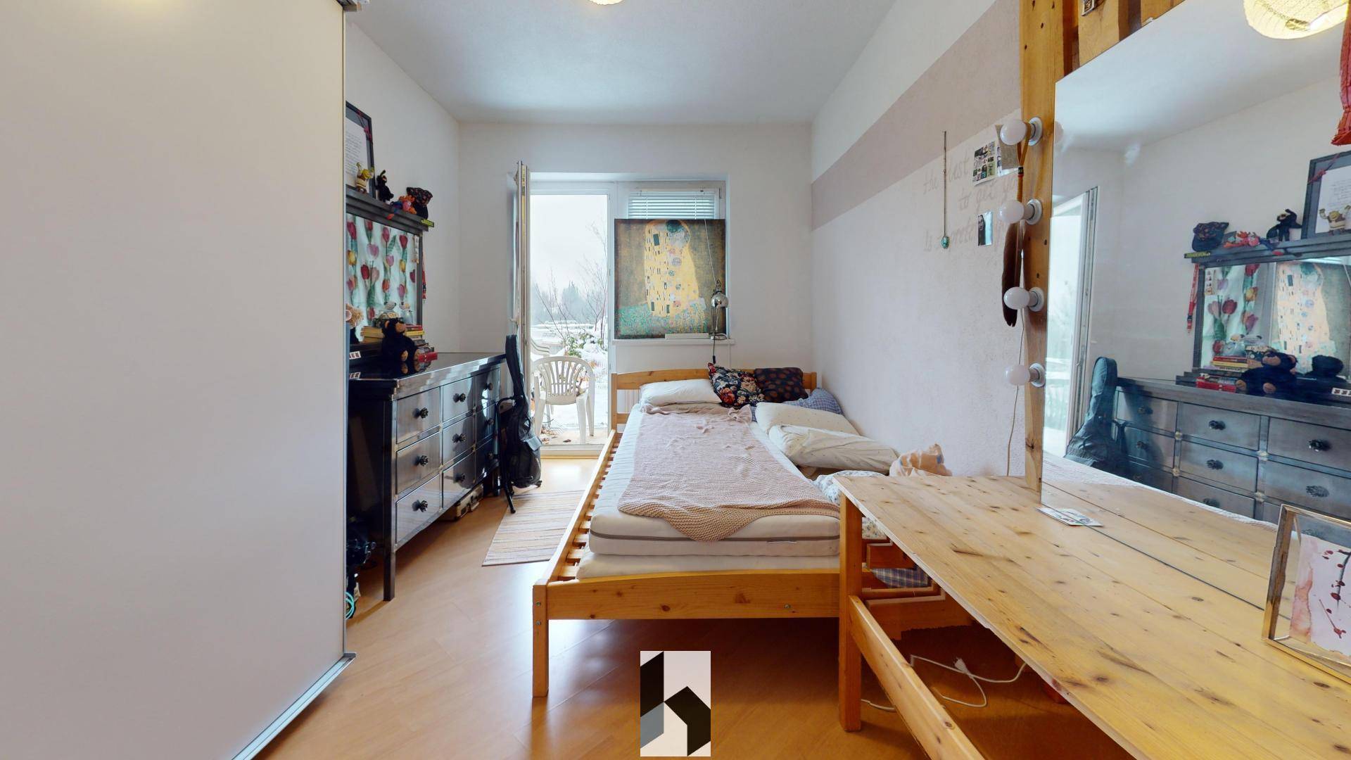 Jugendzimmer mit Einzelbett, Schreibtisch und Zugang zu einem kleinen Balkon.