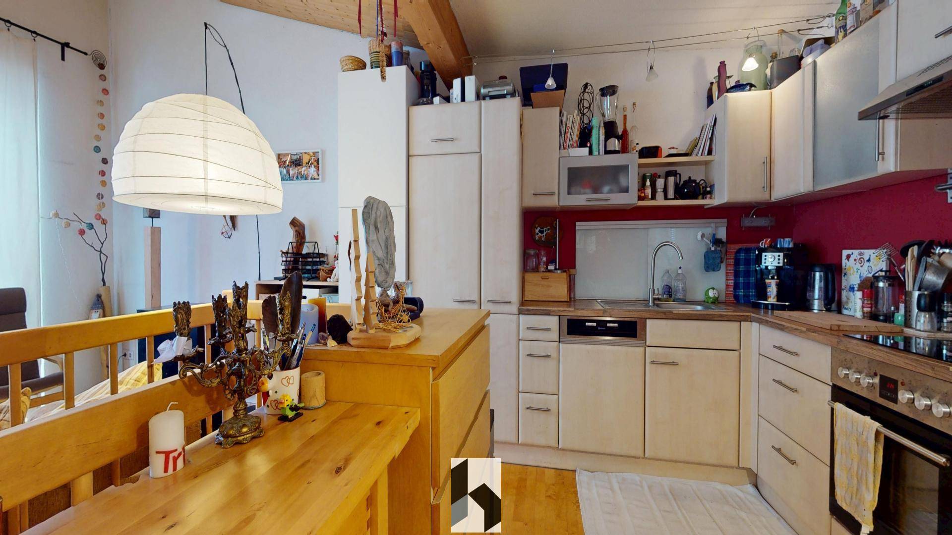 Gemütliche Küche mit Holztisch, Einbauküche und roten Akzentwänden.