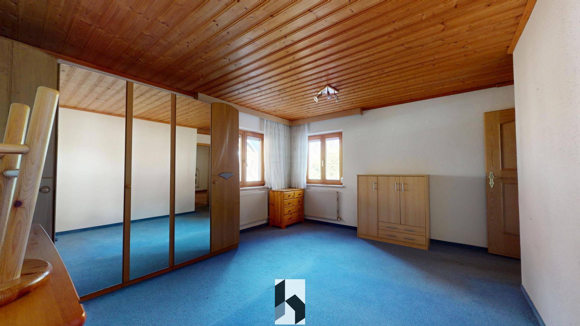 Schlafzimmer mit Teppichboden, Holzdecke und großem Spiegelschrank.