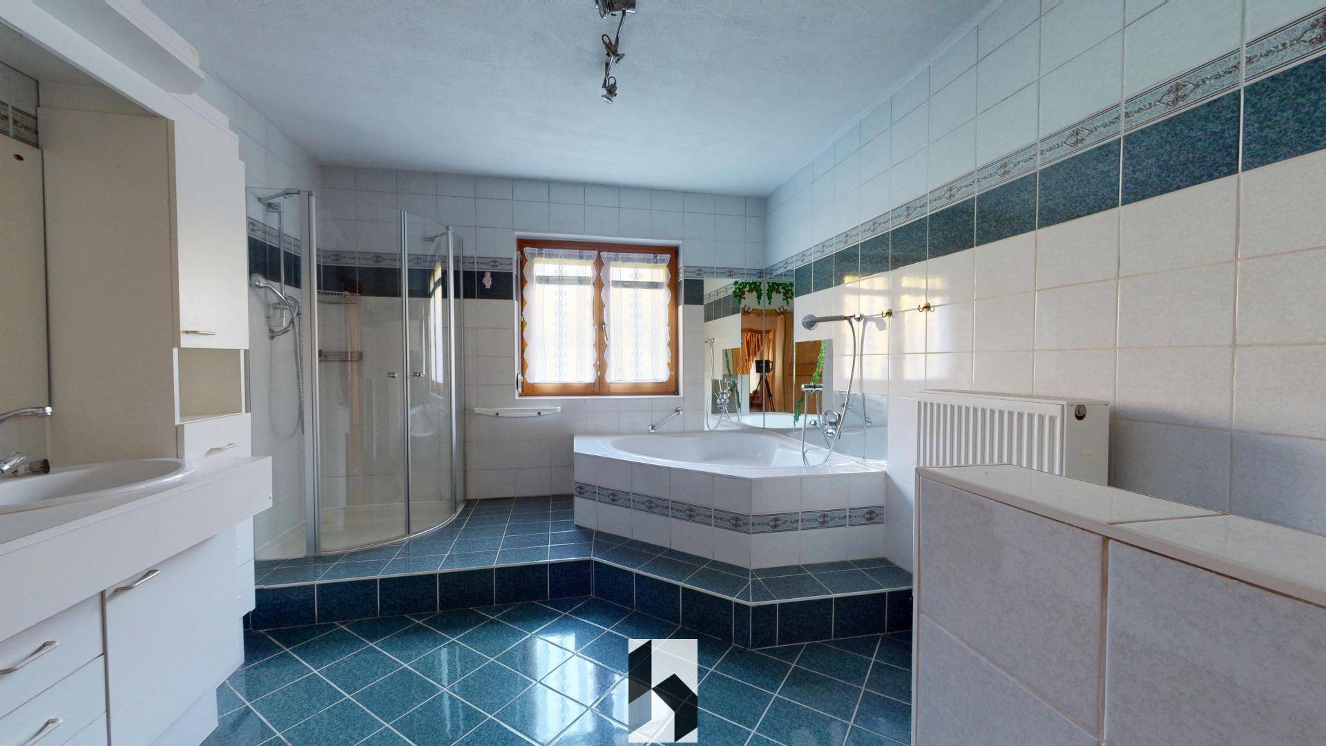 Geräumiges Badezimmer mit Eckbadewanne, separater Dusche und blauen Fliesen.