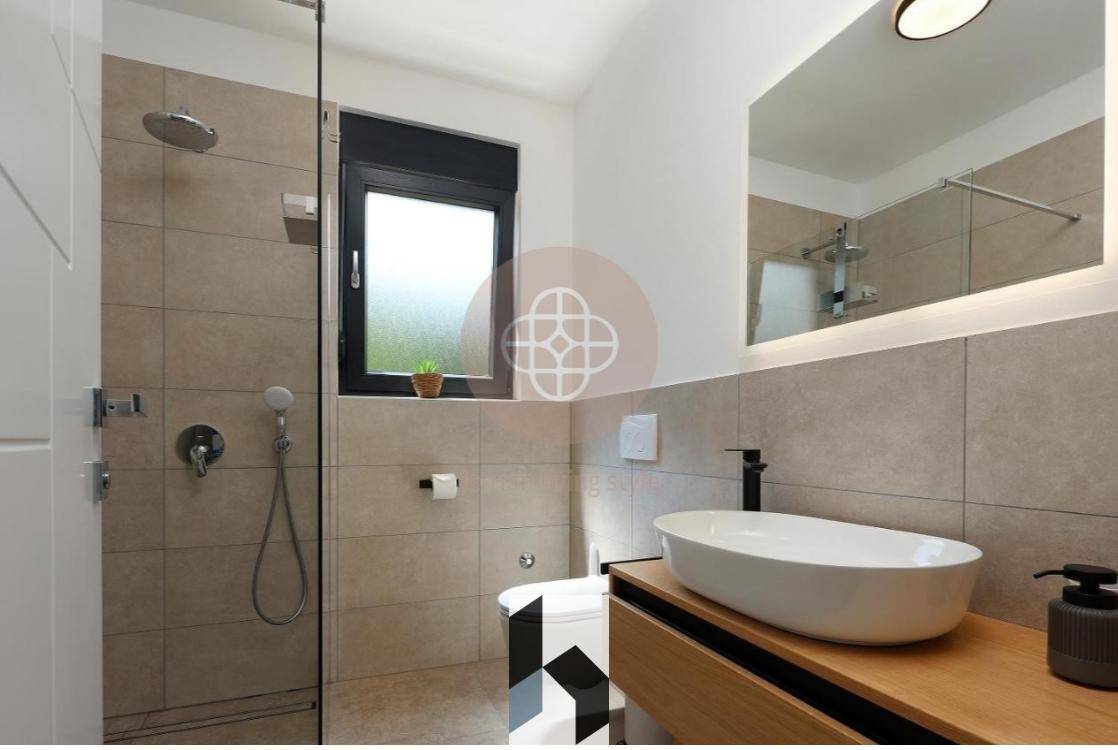 Modernes Badezimmer mit begehbarer Dusche, stilvollem Waschbecken und Fenster für Tageslicht.