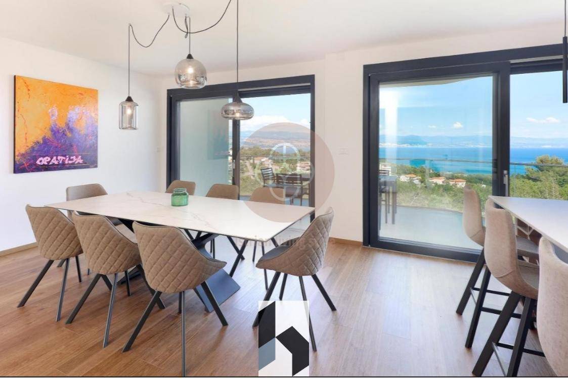 Moderner Essbereich mit großem Tisch, bequemen Stühlen und weitem Blick auf das Meer.
