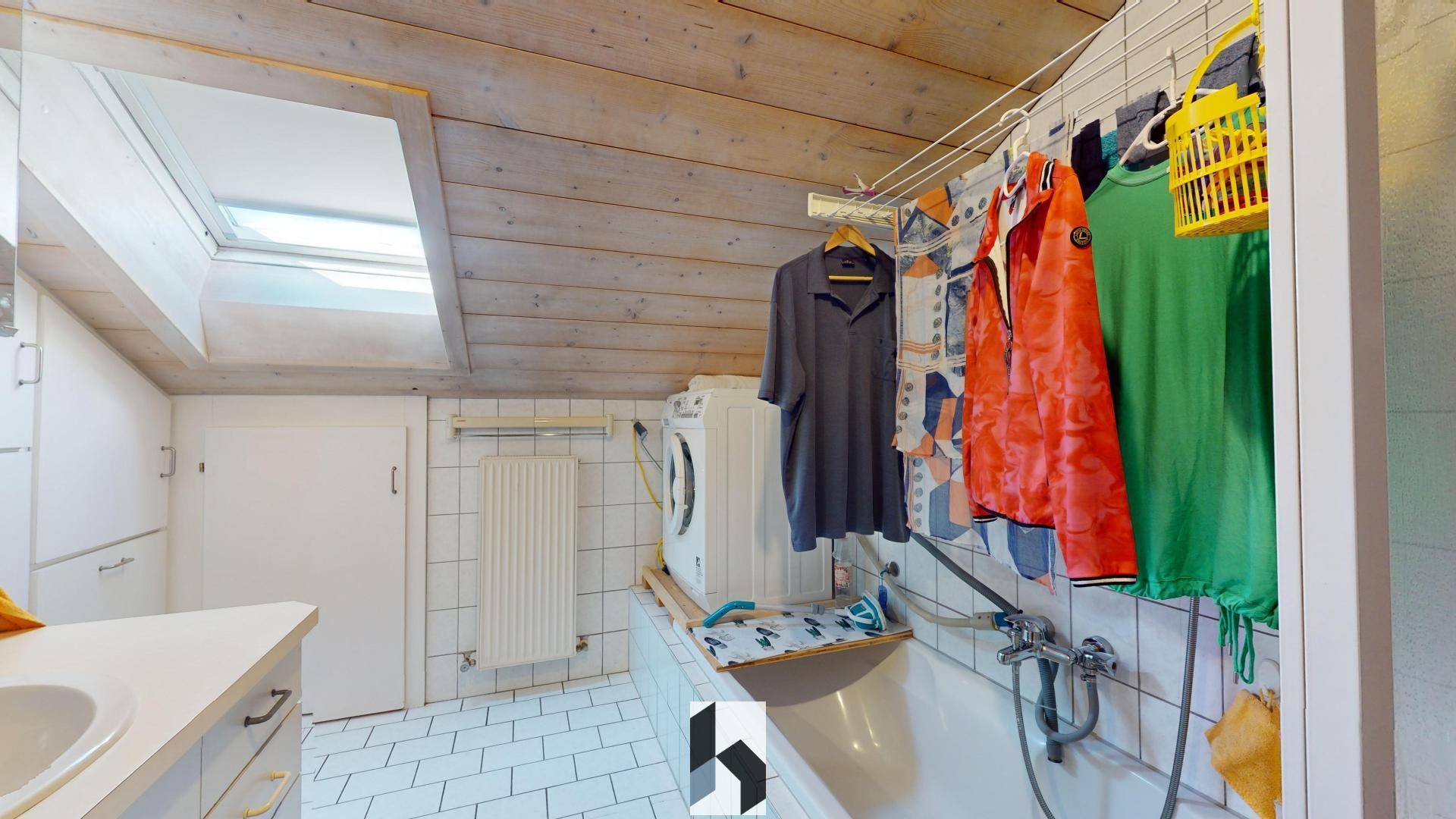 Waschküche im Dachgeschoss mit Badewanne, Waschmaschine und Dachfenster.