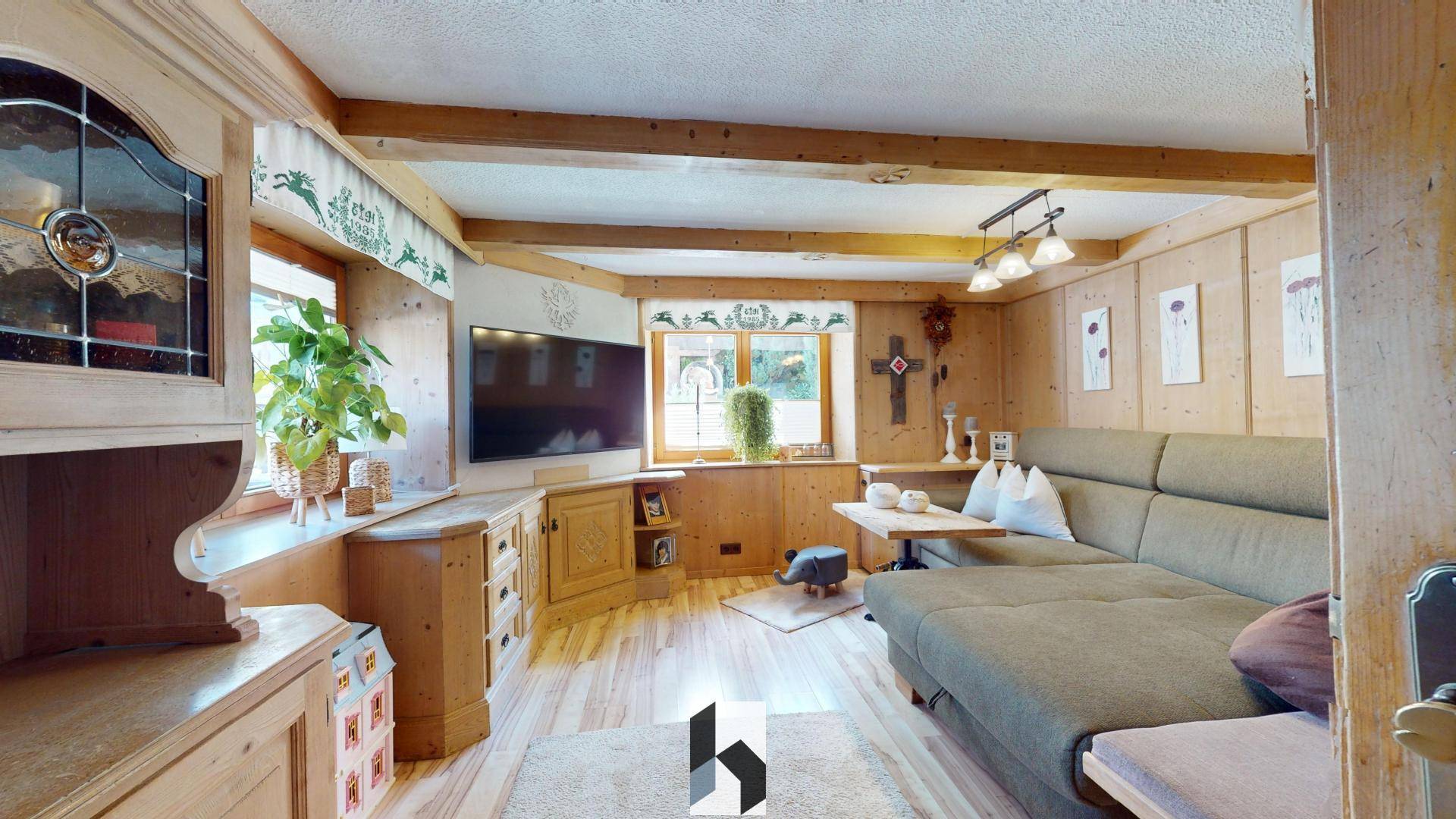 Gemütliches Wohnzimmer im alpinen Stil mit Holzvertäfelung und bequemer Couch.