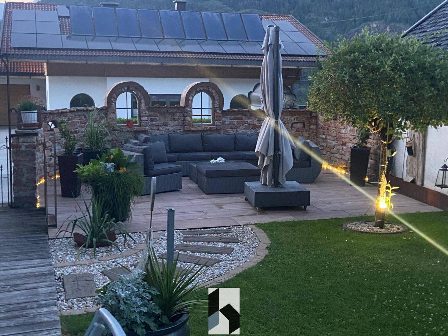Große Terrasse mit Lounge-Möbeln, Garten und Solaranlage auf dem Dach.