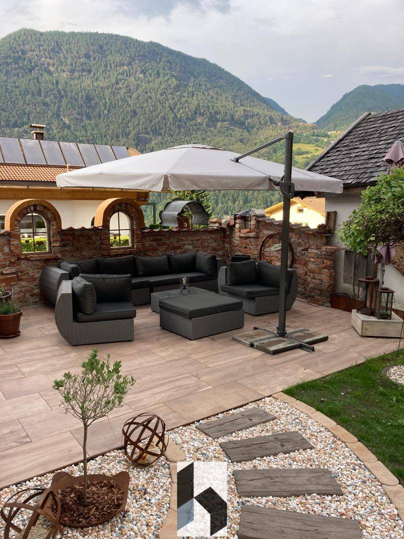 Geräumige Terrasse mit modernen Lounge-Möbeln und Panoramablick auf die Berge.