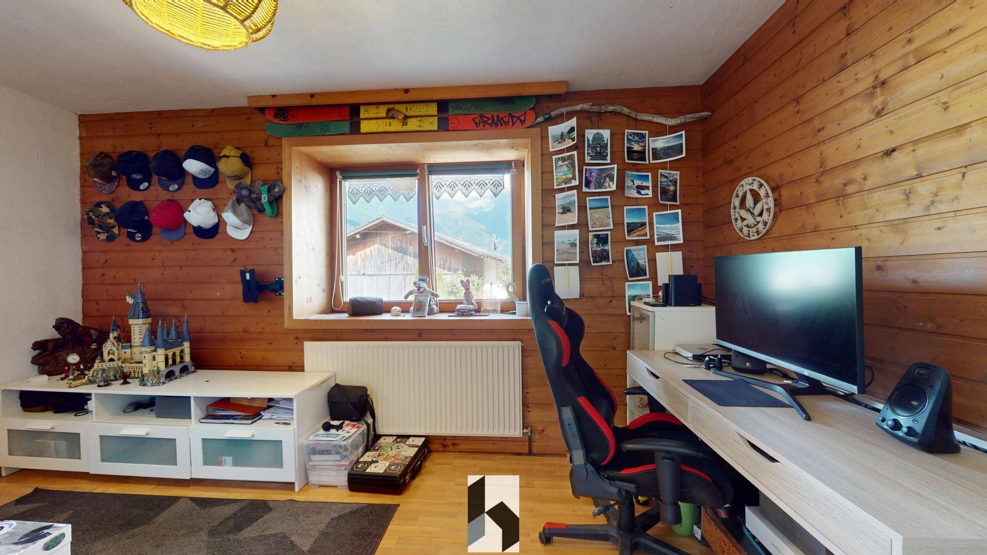 Arbeitszimmer mit Holzvertäfelung, Schreibtisch und Blick auf die Berge.