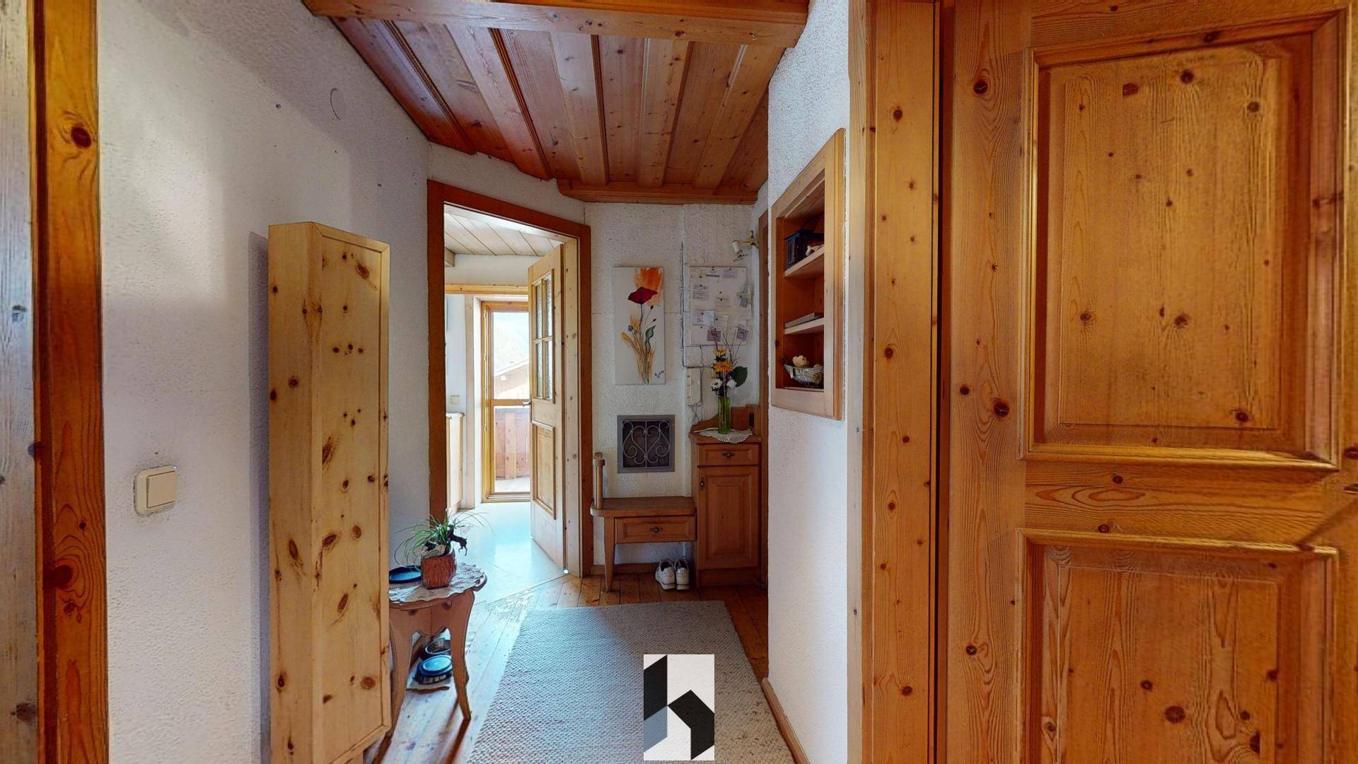 Heller Flur mit Holzboden, Holzvertäfelung und Zugang zu weiteren Räumen.