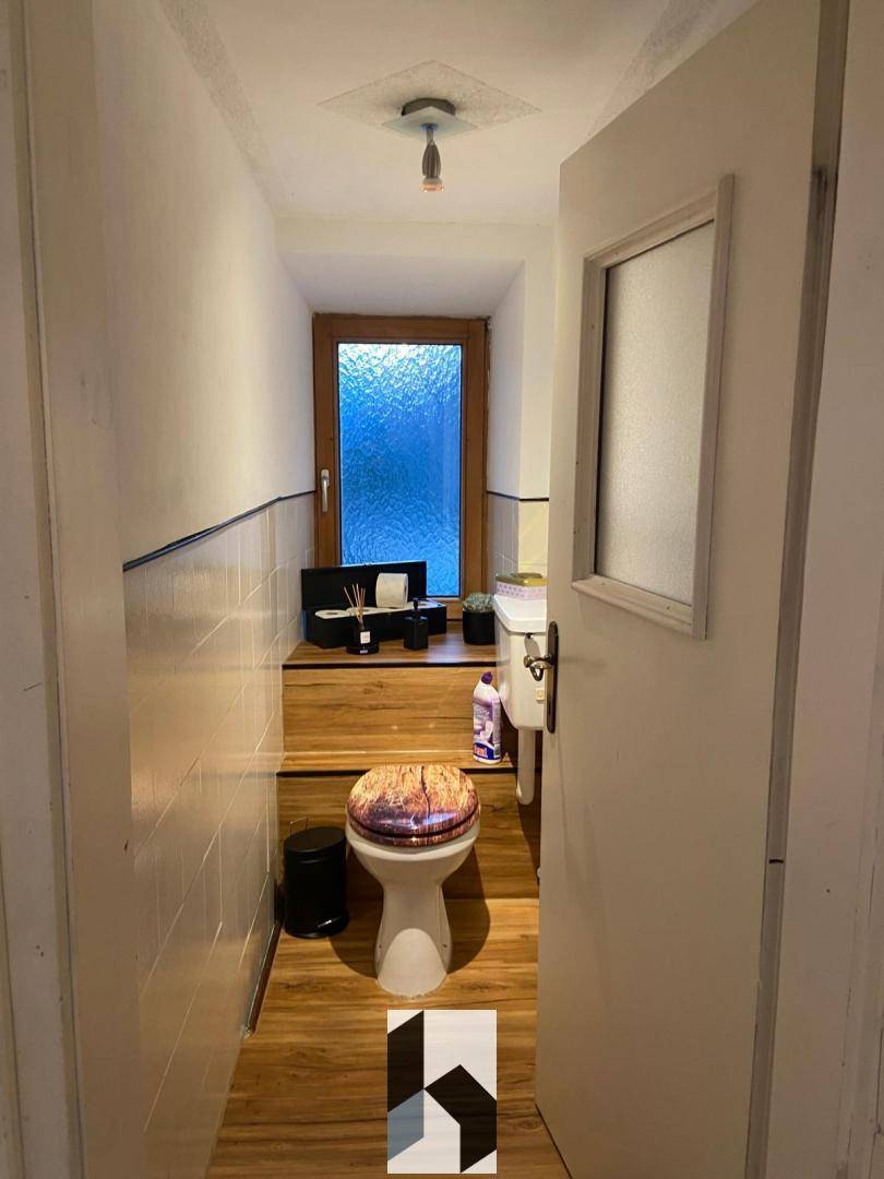 Kleines Gäste-WC mit Fenster, Holzboden und einfacher Ausstattung.