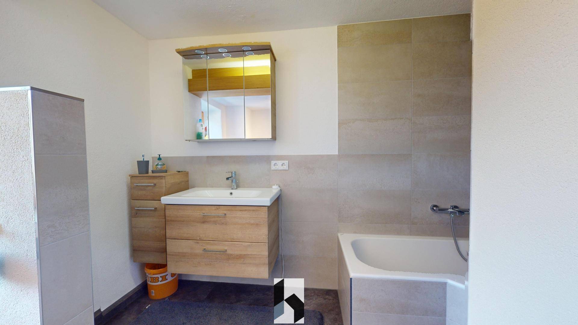 Modernes Badezimmer mit Waschtisch, Badewanne und großen Fliesen.
