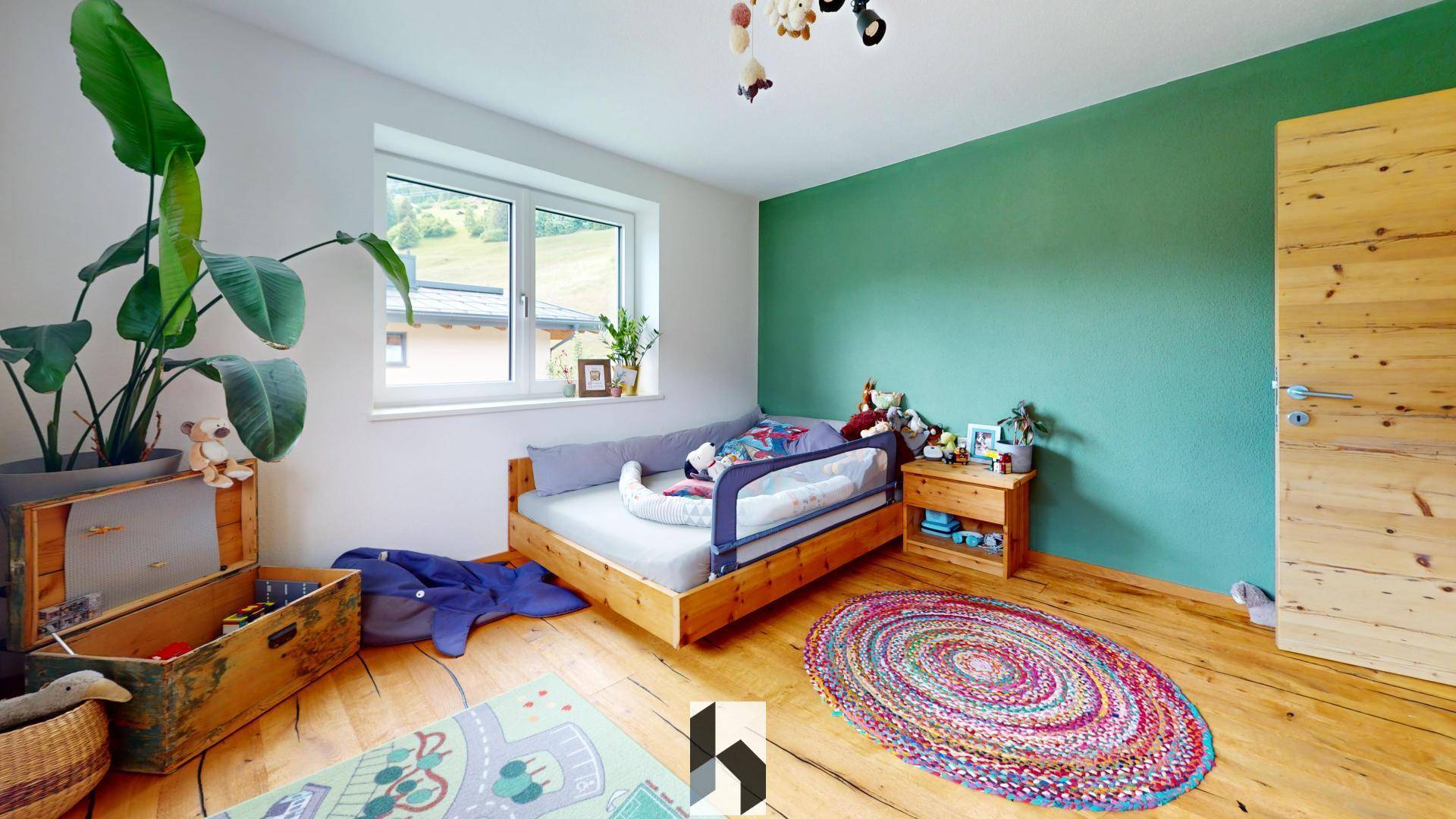 Freundliches Kinderzimmer mit Holzbett, grüner Wand und Spielzeug.