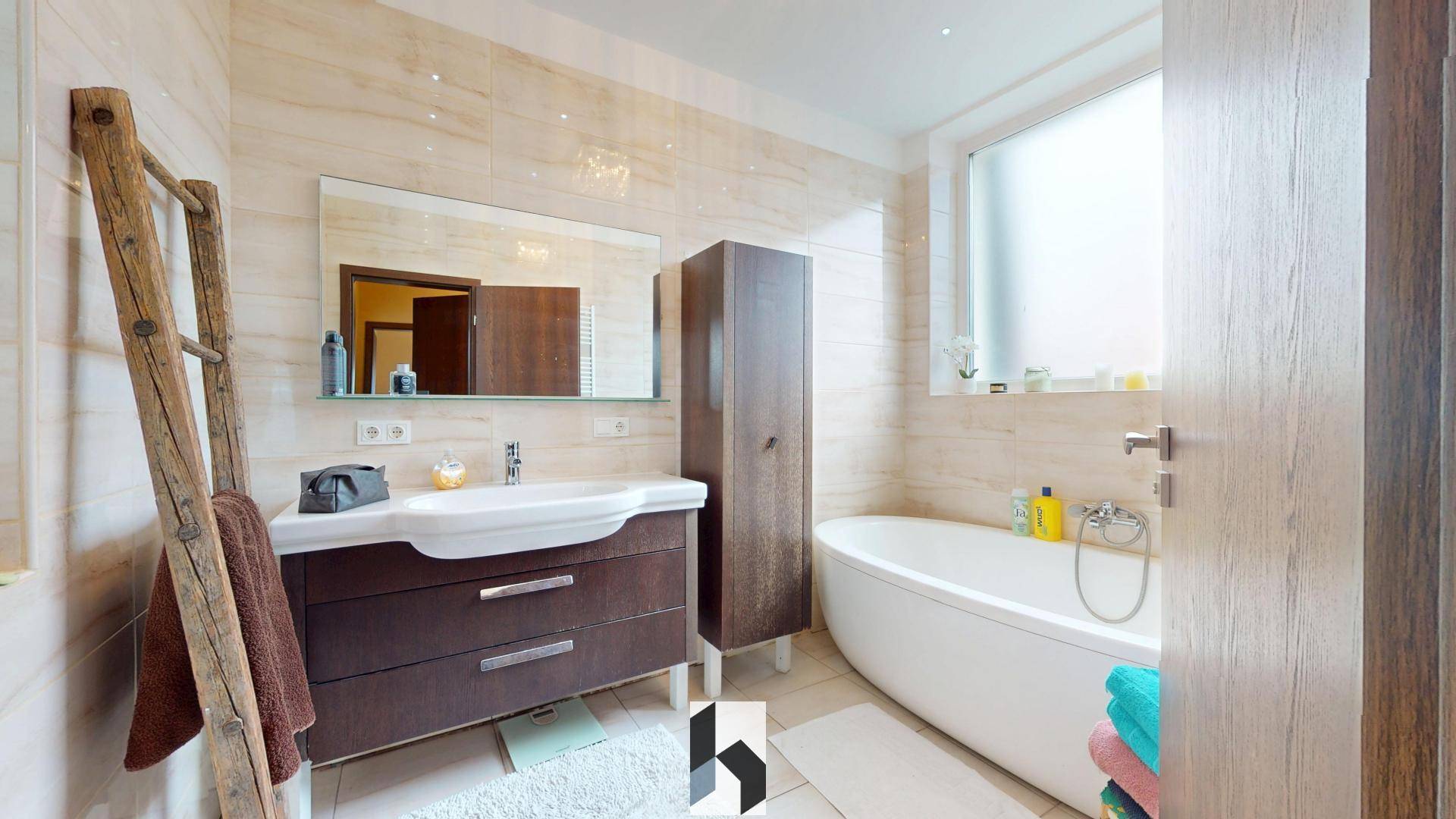 Modernes Badezimmer mit freistehender Badewanne, Einzelwaschbecken, großem Spiegel und einem Fenster für Tageslicht.
