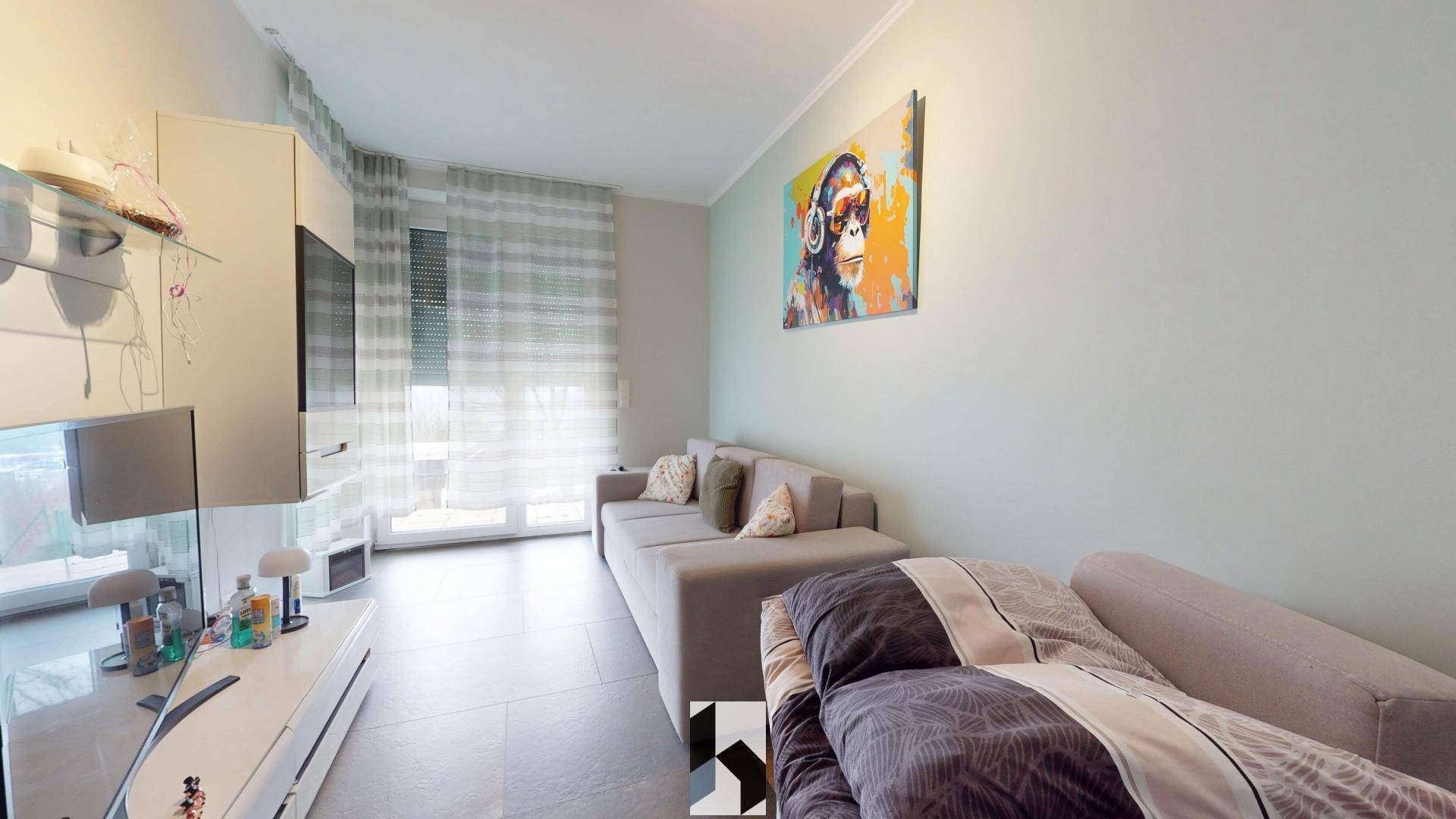 Modernes Wohnzimmer mit beigem Sofa, TV-Möbeln und einem Fenster mit hellen Vorhängen für viel Tageslicht.