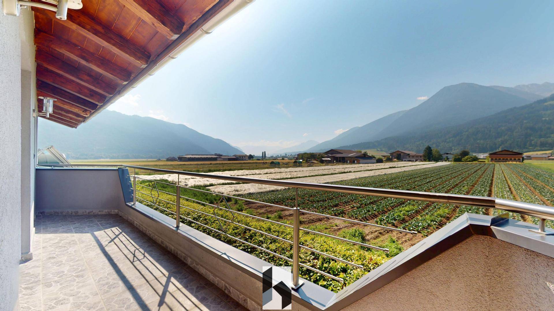 Großer Balkon mit weitem Blick über Felder und die umliegende Berglandschaft.