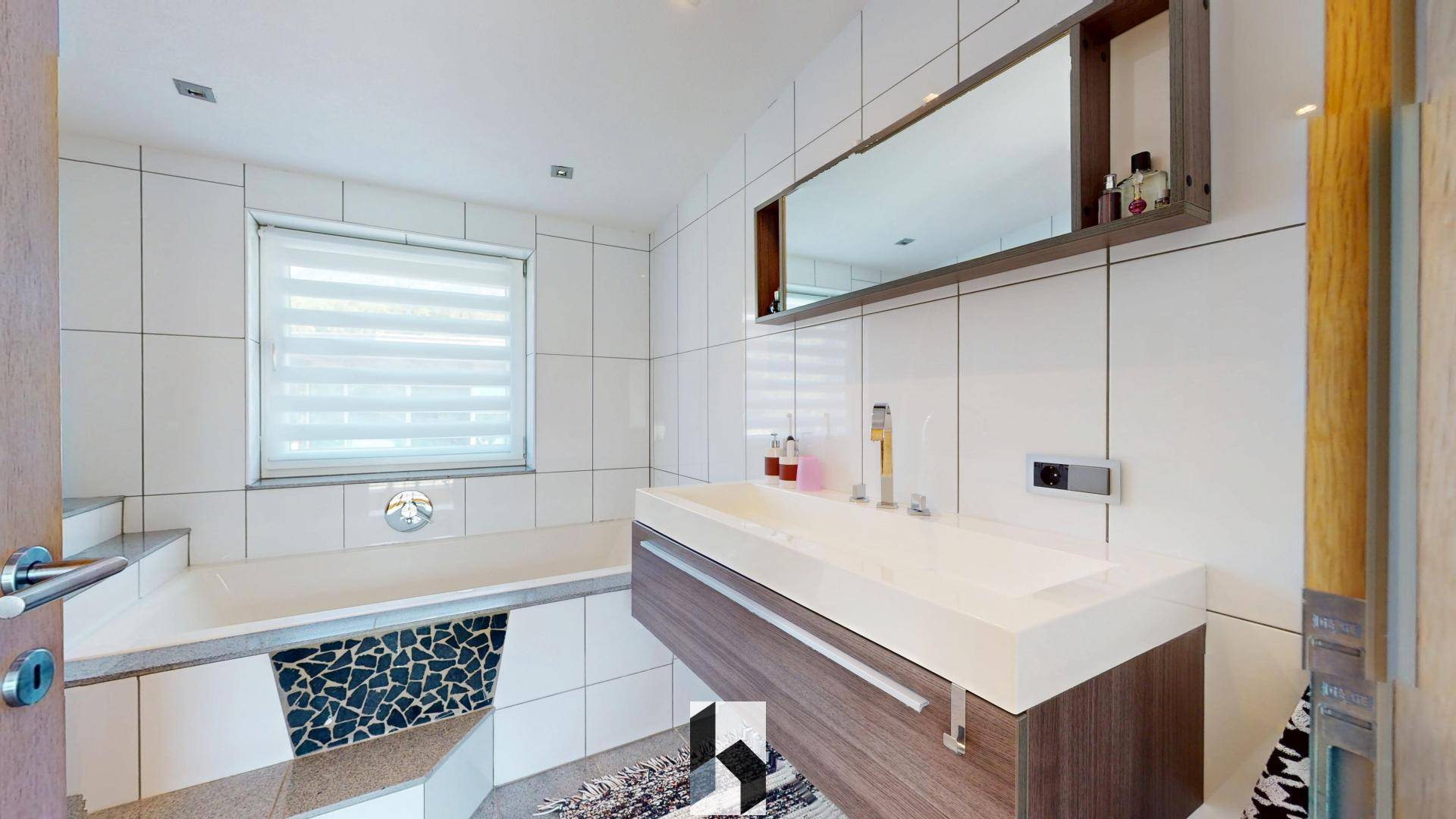 Modernes Badezimmer mit Badewanne, schwebendem Waschtisch und weißen Fliesen.