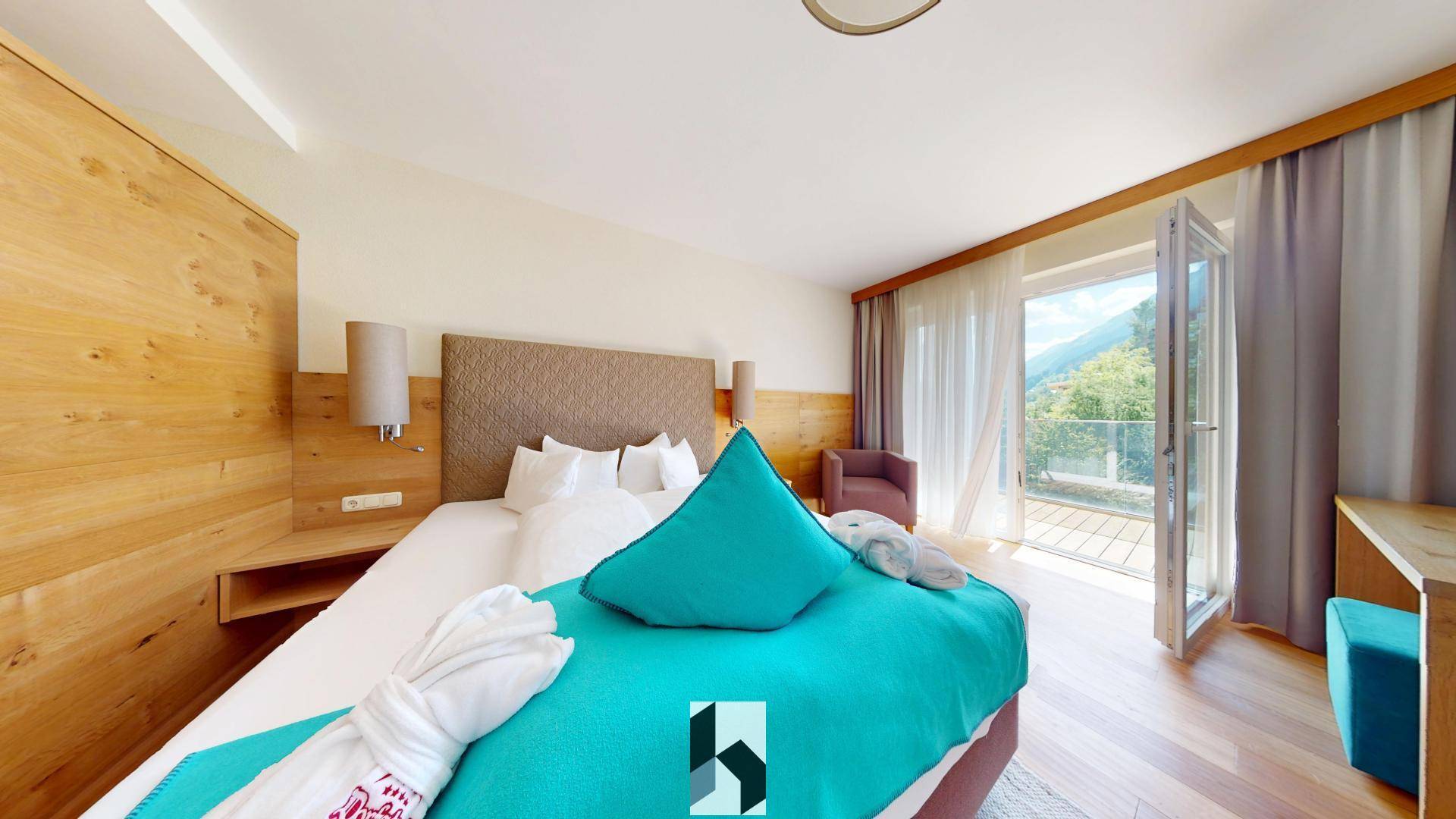 Gemütliches Schlafzimmer mit Holzelementen, großem Bett und direktem Zugang zu einem Balkon mit Bergblick.